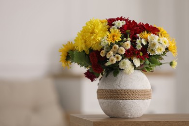 Bouquet of beautiful chrysanthemum flowers on table in room, space for text