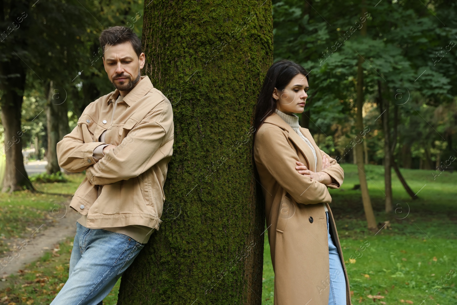 Photo of Upset arguing couple near tree in park. Relationship problems