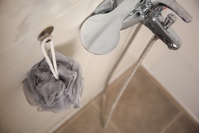 Grey shower puff hanging near faucet in bathroom, above view