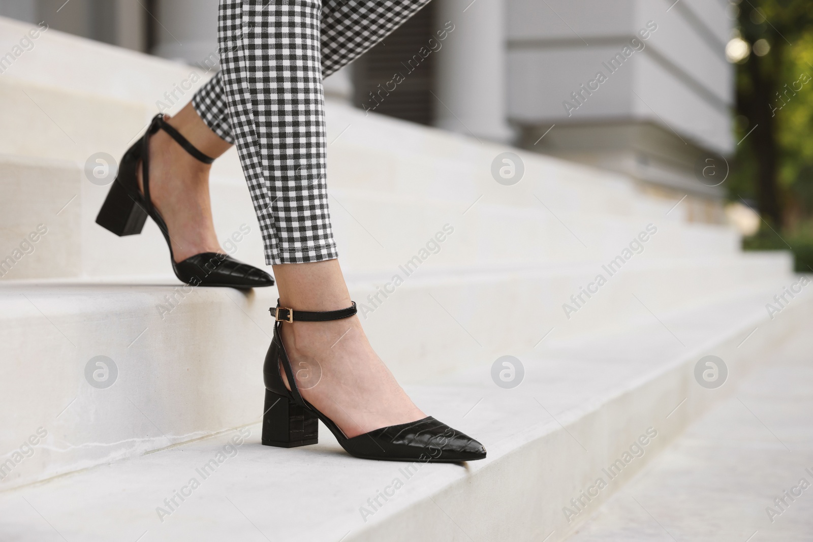 Photo of Woman in stylish black shoes walking down stairs, closeup