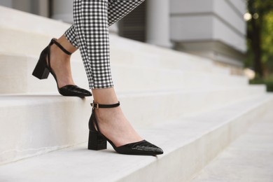 Woman in stylish black shoes walking down stairs, closeup