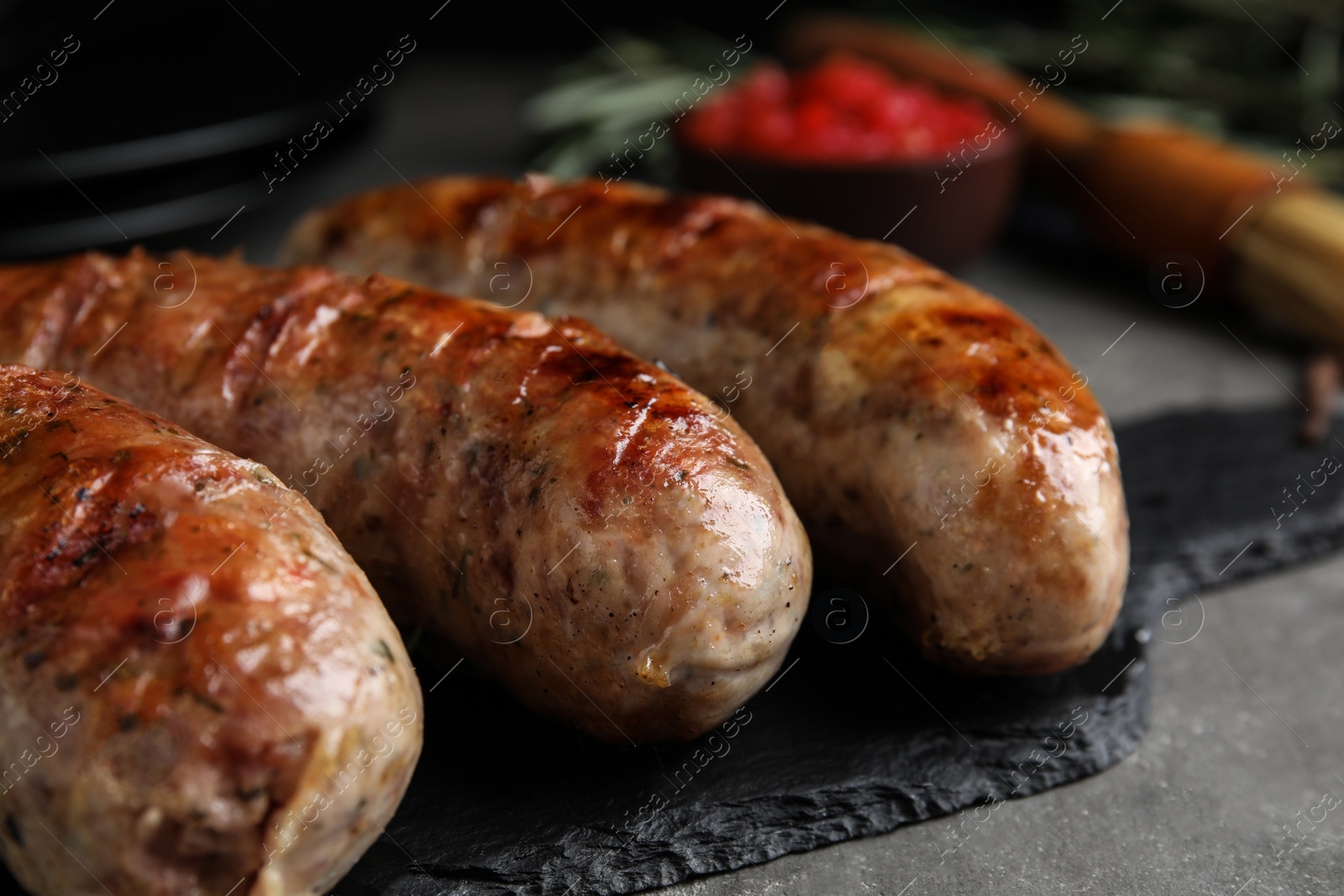 Photo of Tasty grilled sausages on grey table, closeup