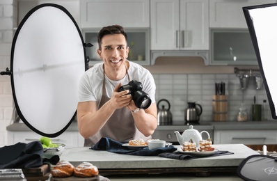 Photo of Young man with professional camera in kitchen. Food photography