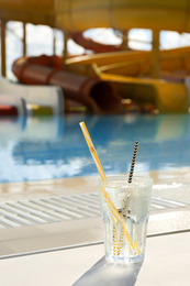 Photo of Glass of refreshing drink near swimming pool