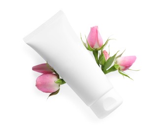 Tube of hand cream and roses on white background, top view