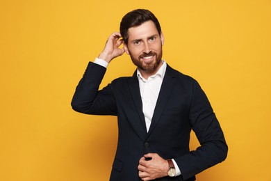 Photo of Portrait of smiling bearded man in suit on orange background