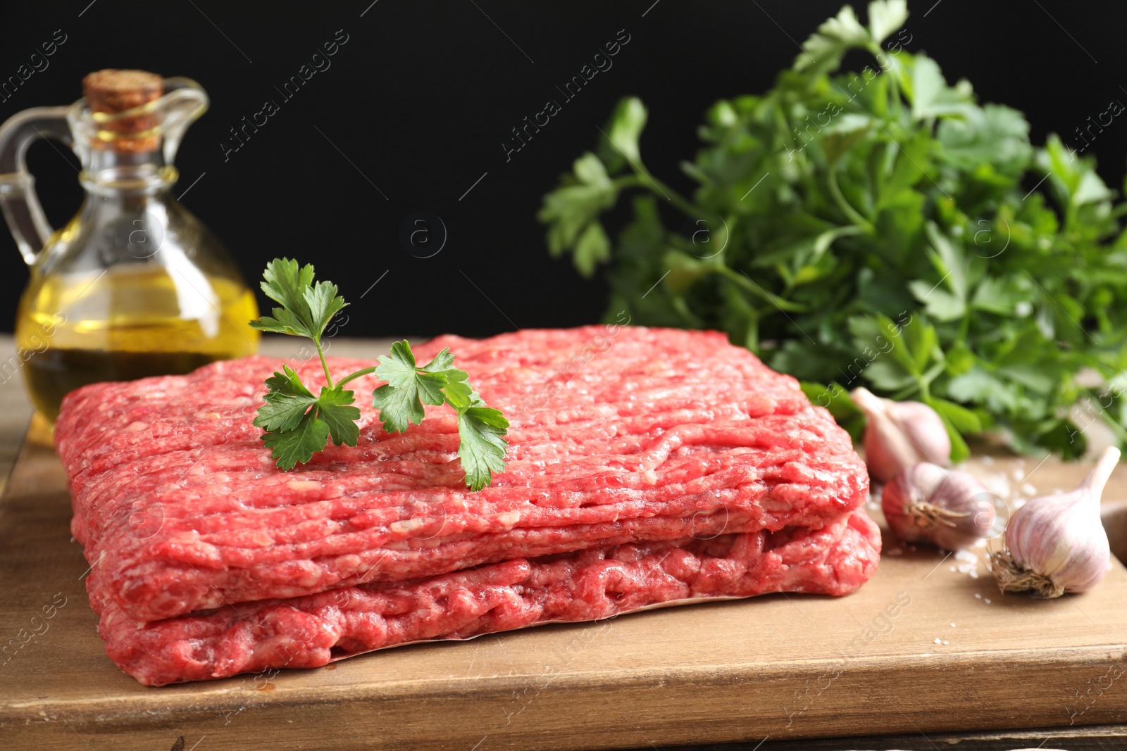 Photo of Raw ground meat, garlic, oil and parsley on table