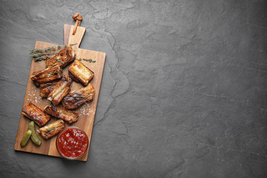 Photo of Delicious grilled ribs served on grey table, top view. Space for text