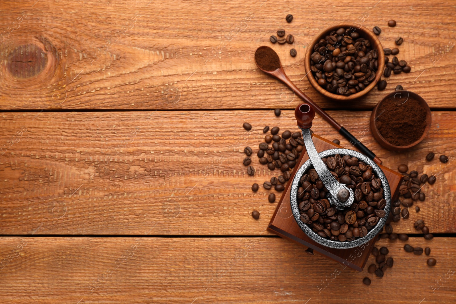 Photo of Vintage manual coffee grinder with beans and powder on wooden table, flat lay. Space for text