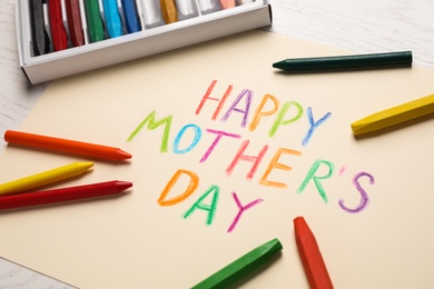 Handmade greeting card for Mother's Day and crayons on light wooden table, closeup