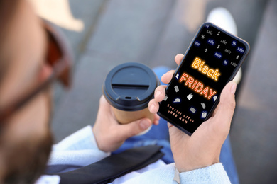 Image of Black Friday. Man shopping online using smartphone, closeup