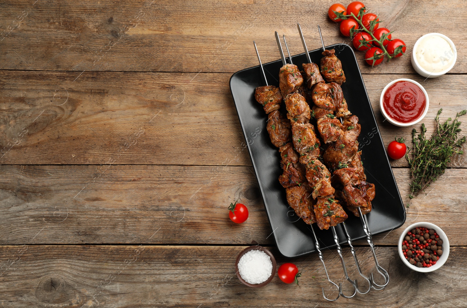 Photo of Metal skewers with delicious meat and vegetables served on wooden table, flat lay. Space for text