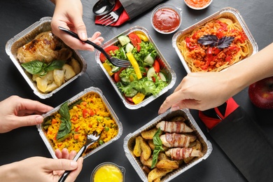 Photo of People eating from lunchboxes at grey table, top view. Healthy food delivery