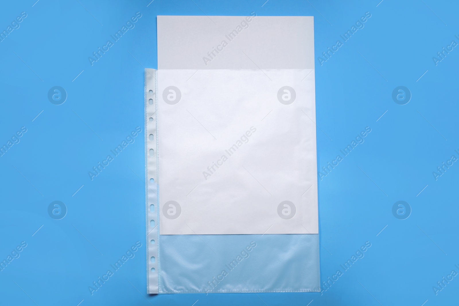 Photo of Punched pocket with paper sheet on light blue background, top view. Space for text