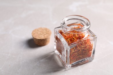 Photo of Aromatic saffron, glass jar and lid on light gray table, space for text