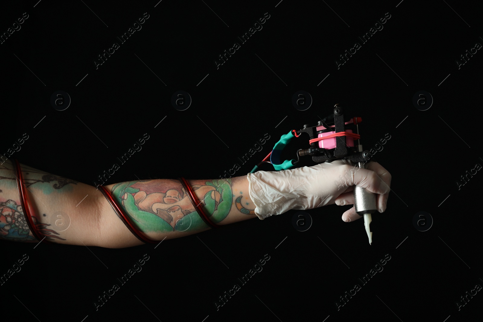 Photo of Tattoo artist with professional machine on black background, closeup