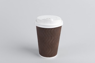 Photo of Brown paper cup with plastic lid on light background. Coffee to go