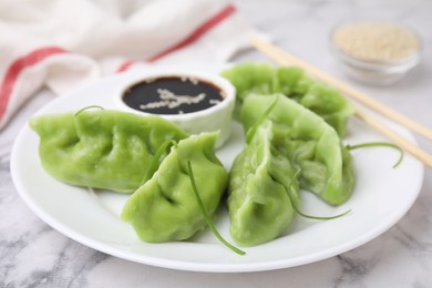 Photo of Delicious green dumplings (gyozas) and soy sauce on white marble table, closeup