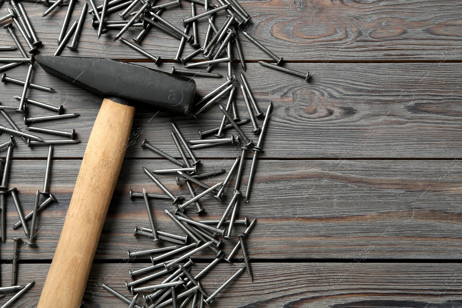 Photo of Hammer and metal nails on black wooden table, flat lay. Space for text