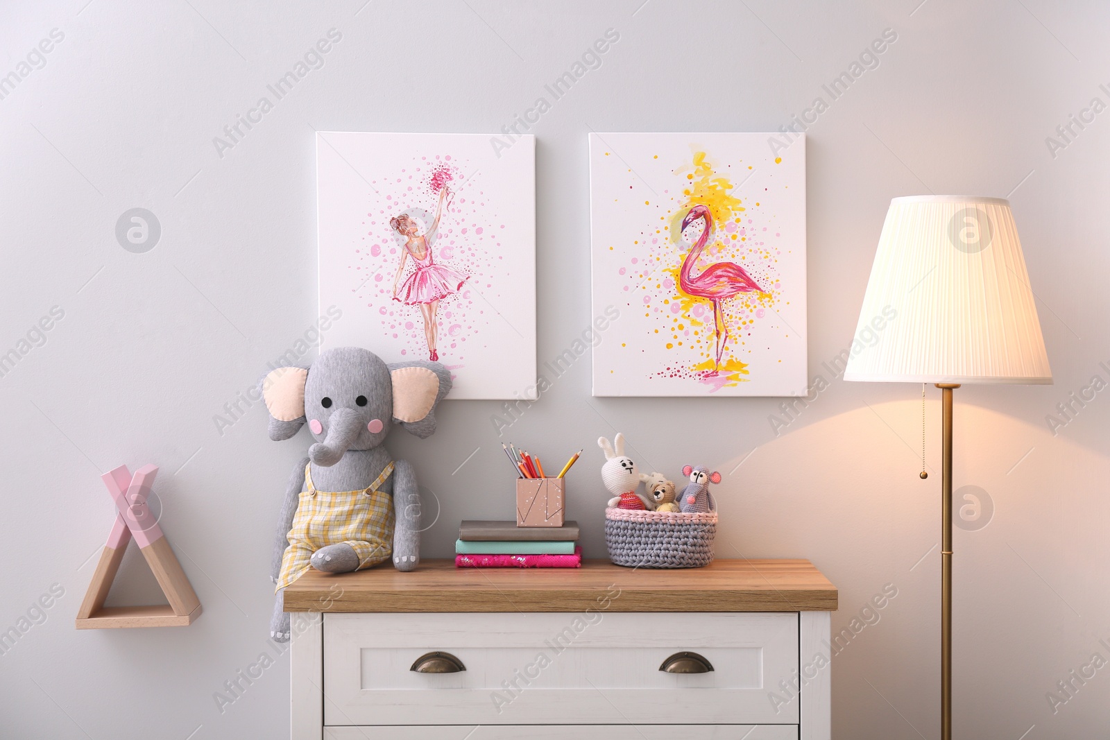 Photo of Chest of drawers and beautiful pictures in children's room. Interior design