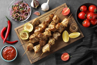 Photo of Delicious fresh shish kebabs with sauce served on grey table, flat lay