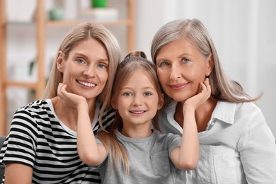 Photo of Three generations. Happy grandmother, her daughter and granddaughter at home