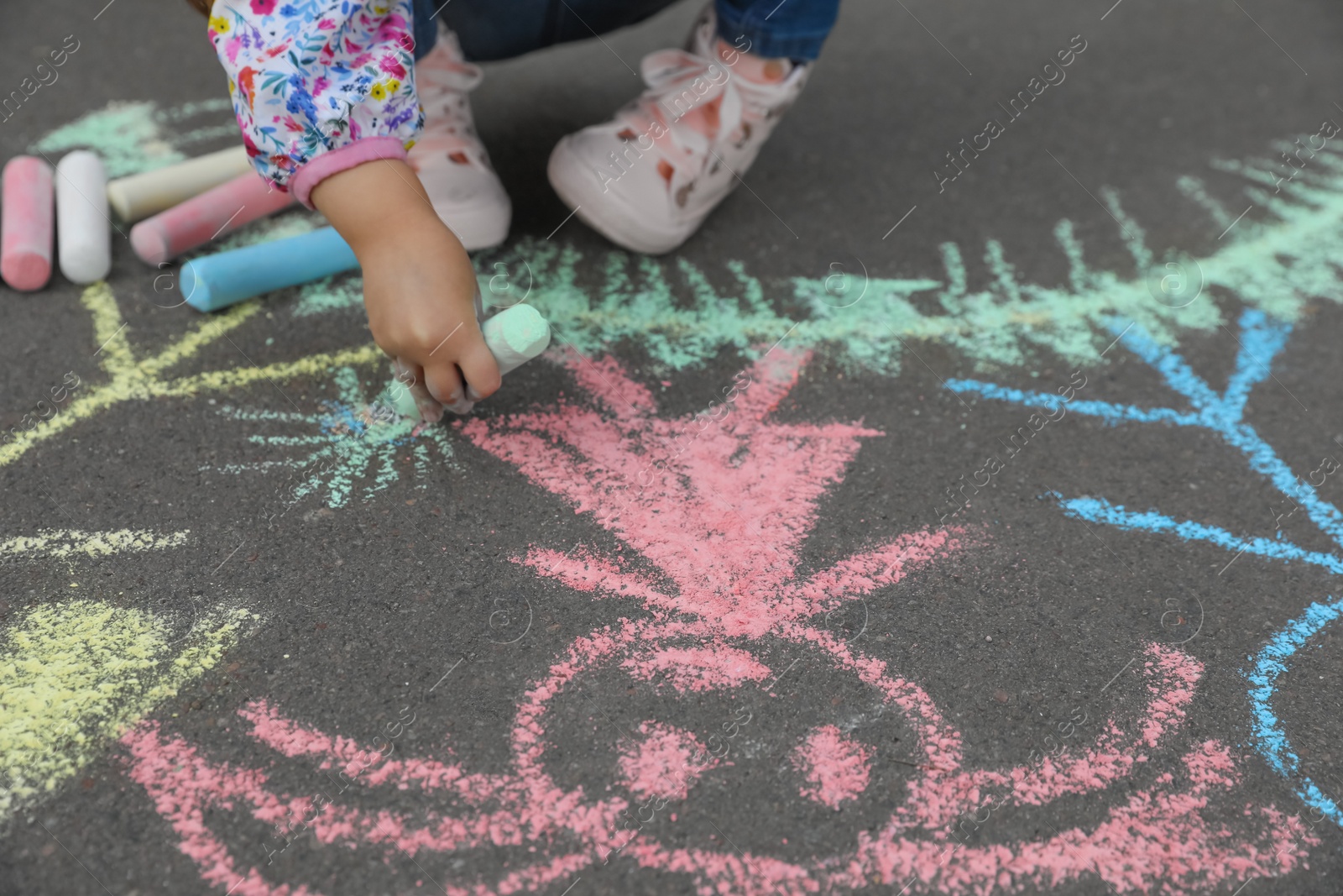 Photo of Child drawing family with chalk on asphalt, closeup