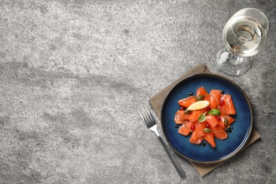 Photo of Salmon carpaccio with capers, cranberries, basil and lemon served on grey table. Space for text