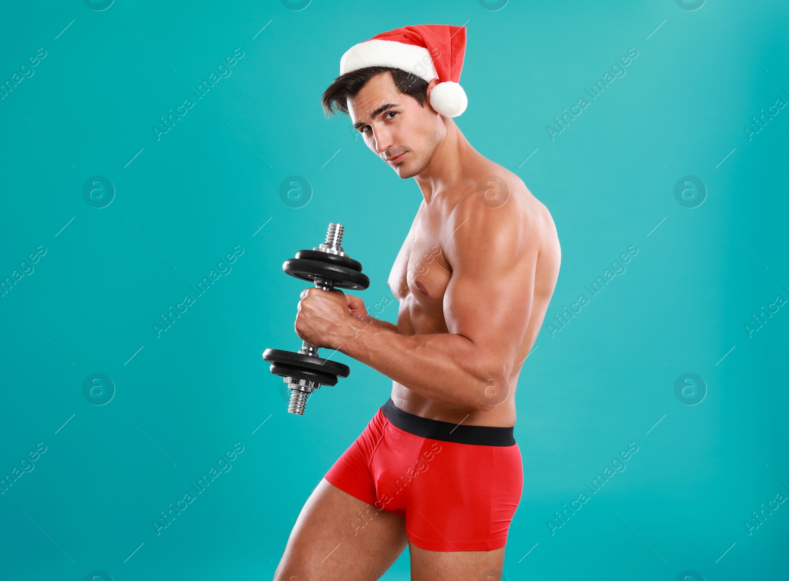 Photo of Sexy shirtless Santa Claus with dumbbell on blue background