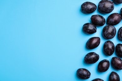 Photo of Delicious ripe plums on light blue background, flat lay. Space for text