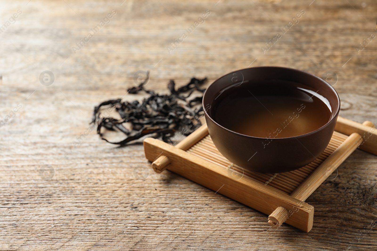 Photo of Cup of Da Hong Pao oolong and tea leaves on table, space for text