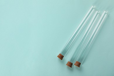 Photo of Test tubes on turquoise background, top view and space for text. Laboratory glassware