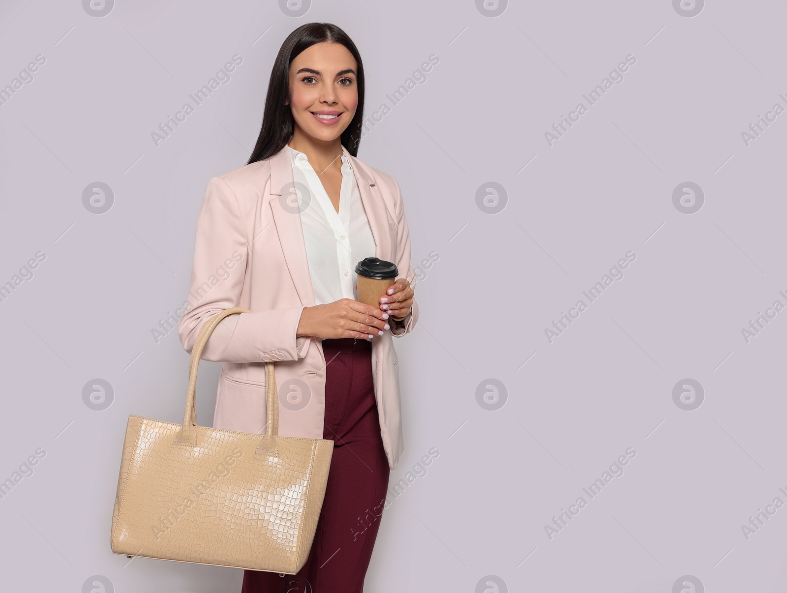 Photo of Young woman with stylish bag and cup of hot drink on white background