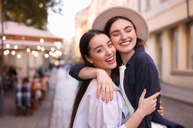 Photo of Happy friends hugging on city street. Space for text