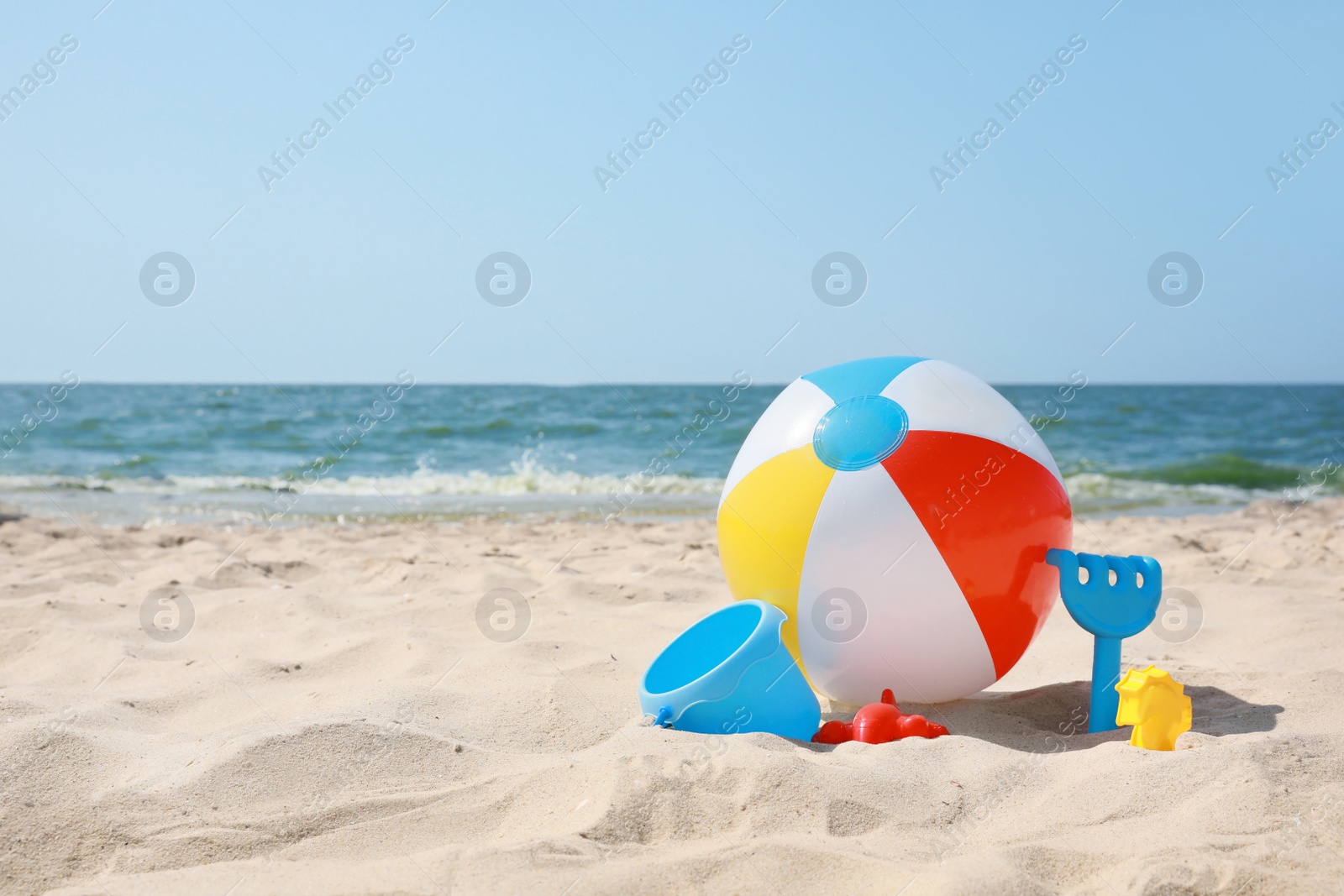 Photo of Many different sand toys and beach ball near sea, space for text