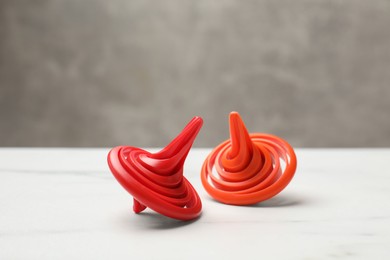 Photo of Bright spinning tops on white table, closeup