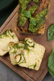 Photo of Freshly baked pesto bread with basil served on grey table, flat lay