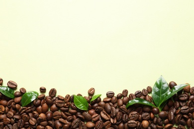 Photo of Fresh green coffee leaves and beans on light green background, flat lay. Space for text