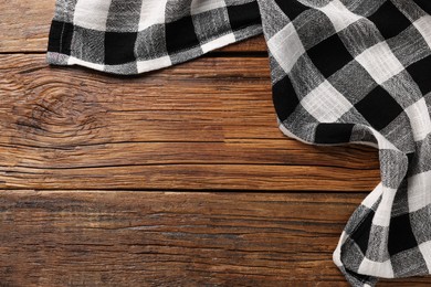 Photo of Black checkered tablecloth on wooden table, top view. Space for text