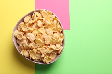 Photo of Bowl of tasty crispy corn flakes on color background, top view. Space for text