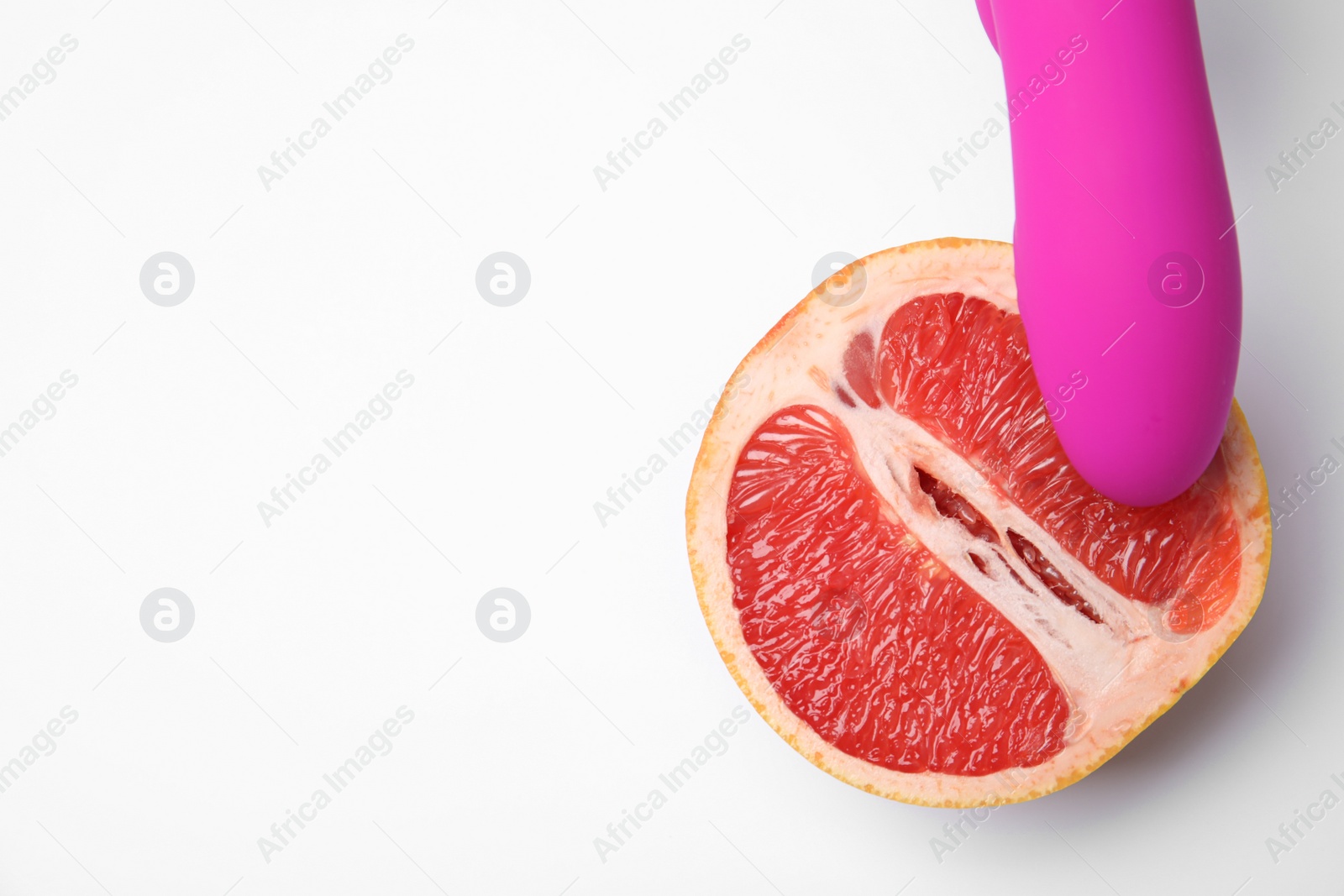 Photo of Half of grapefruit and purple vibrator on white background, top view. Sex concept