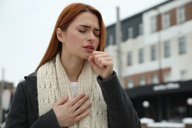 Photo of Beautiful young woman coughing outdoors, space for text. Cold symptoms