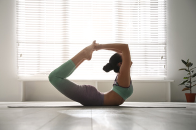 Photo of Woman practicing bow asana in yoga studio. Dhanurasana pose