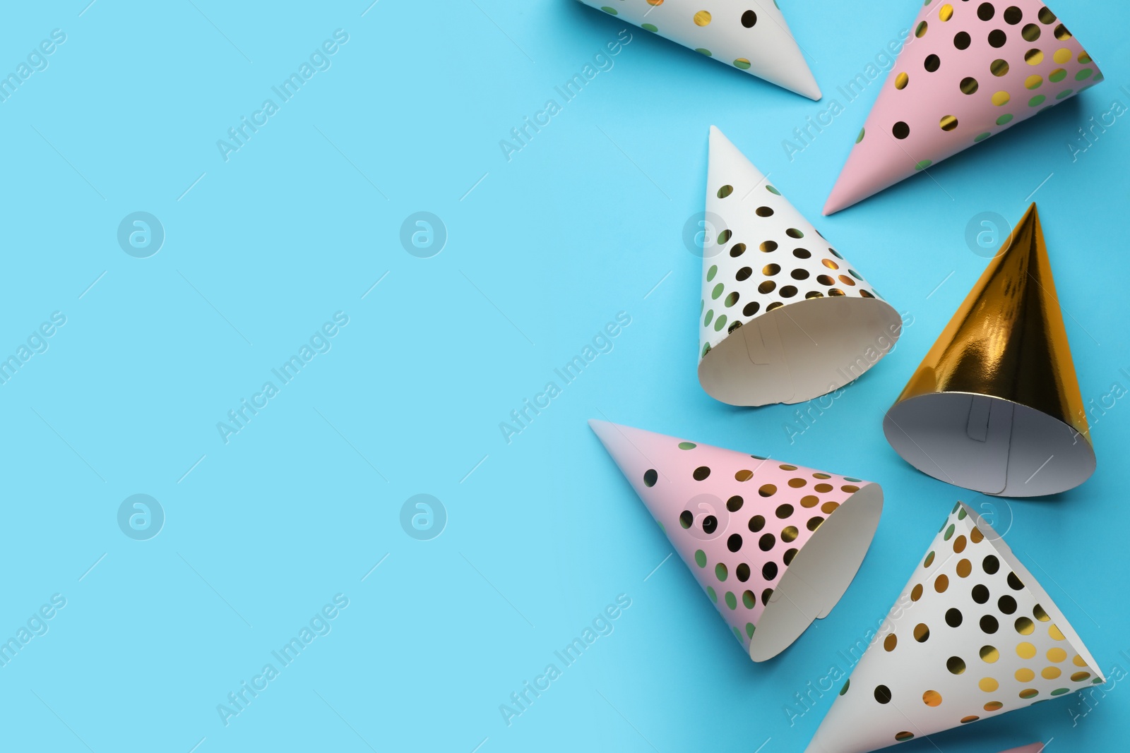 Photo of Bright party hats on light blue background, flat lay. Space for text