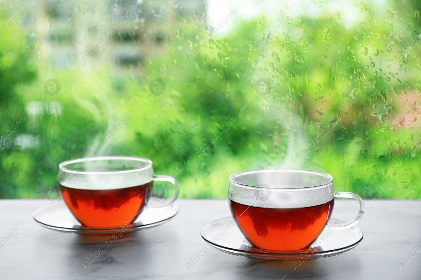 Image of Cups of hot drink near window on rainy day