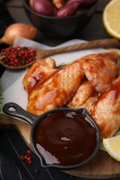 Photo of Fresh marinade and raw chicken wings on table, closeup