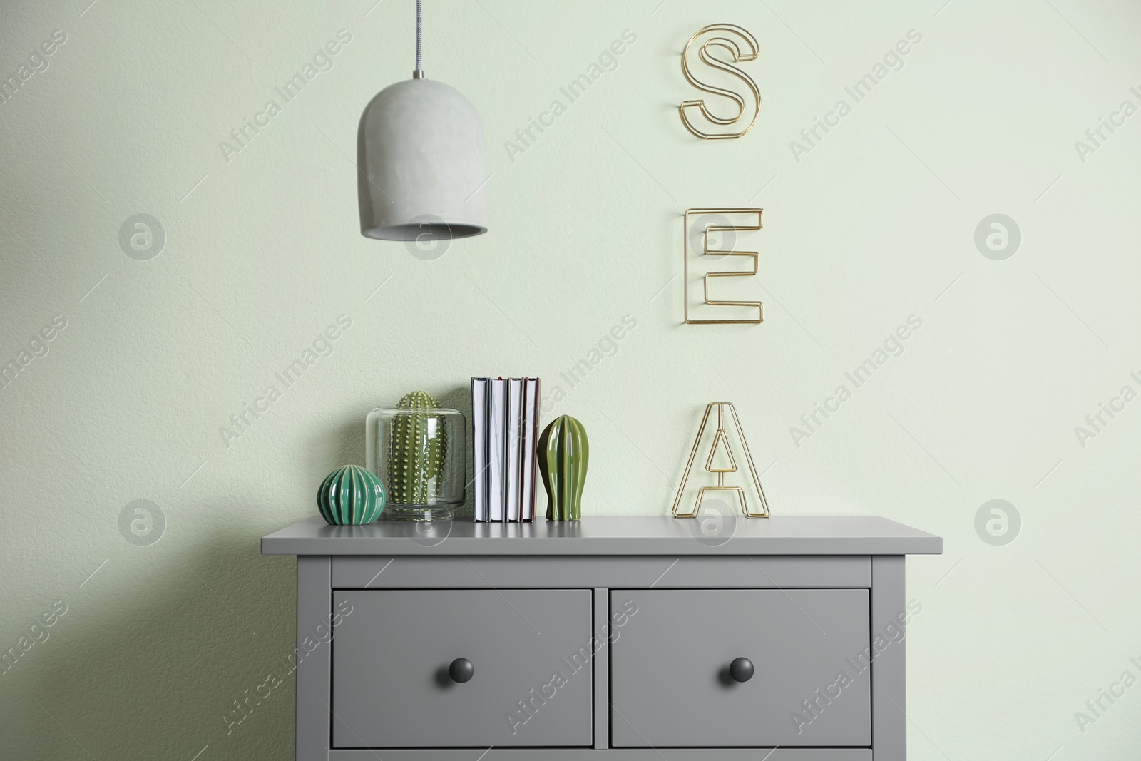 Photo of Grey chest of drawers near light wall in room