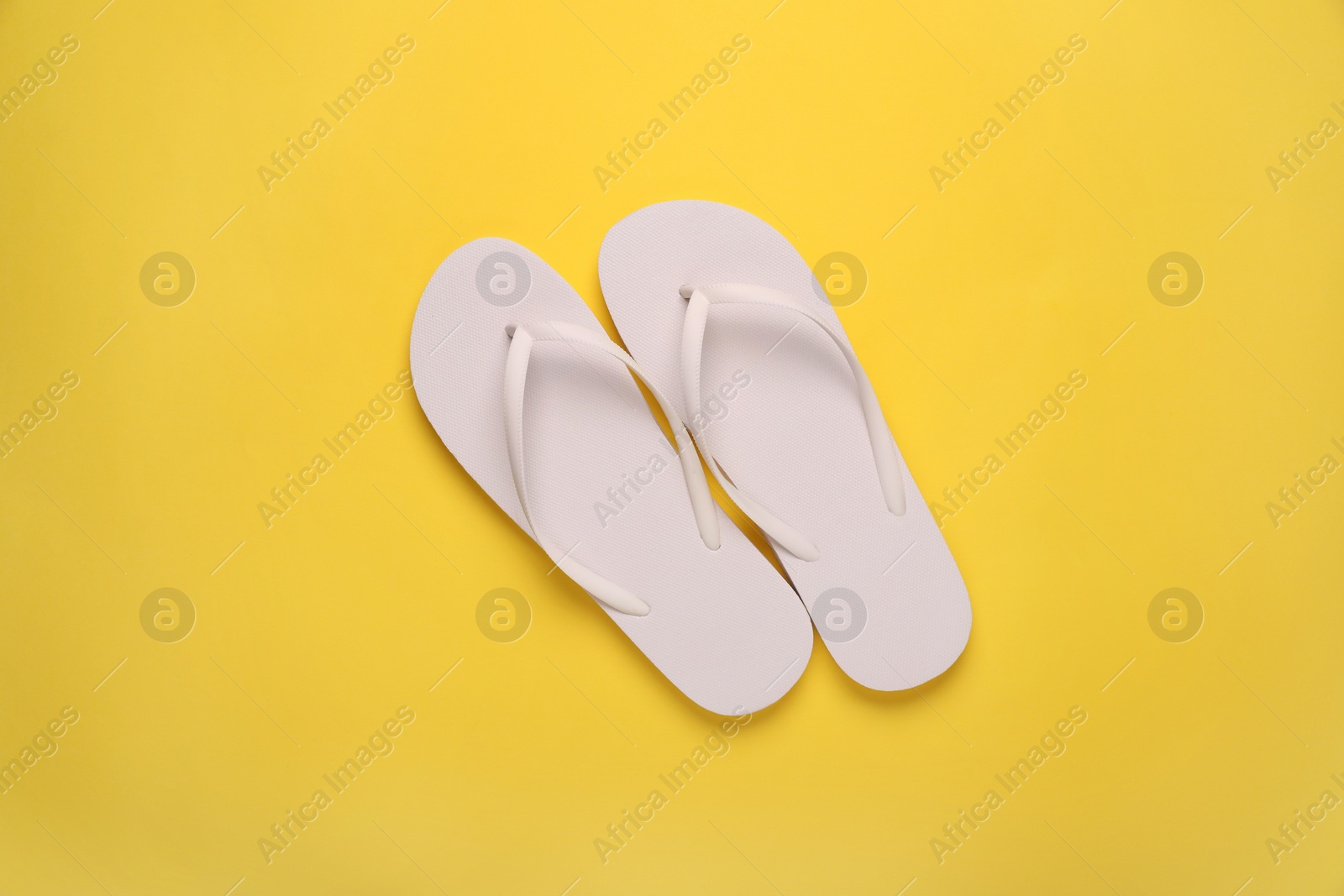 Photo of Stylish flip flops on yellow background, top view