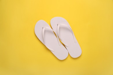 Stylish flip flops on yellow background, top view