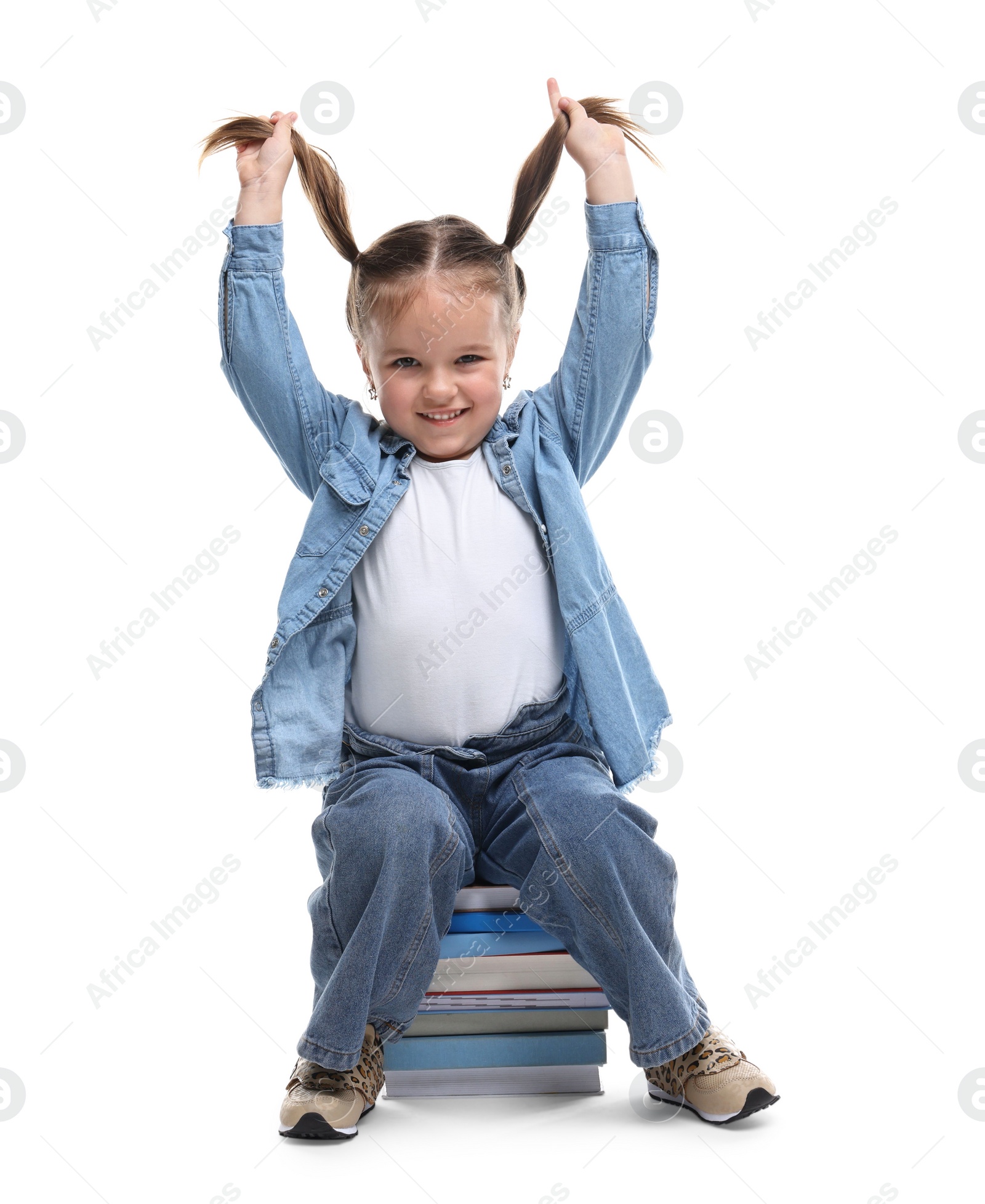 Photo of Cute little girl sitting on stack of books against white background